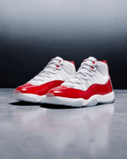 Plugmarket Air Jordan 11 Retro Cherry sneakers with white mesh uppers and patent leather red overlays.